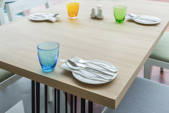 wooden dinning table with colorful set for meal in restaurant interior