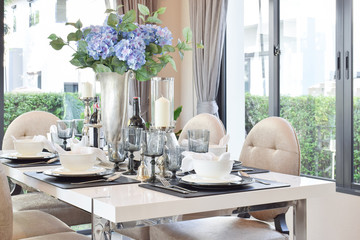 dining wooden table and comfortable chairs in modern home with elegant table setting