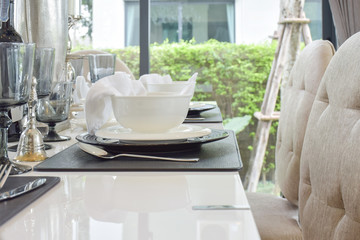 dining wooden table and comfortable chairs in modern home with elegant table setting