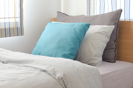 Turquoise and gray pillow on bed with stripe pattern bedding style