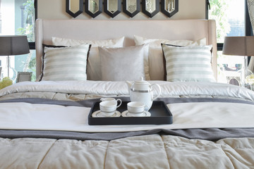 Decorative tray with black tray of tea set on the bed in modern bedroom