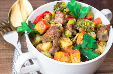 closeup beef meat stewed with vegetables in ceramic pot on wooden background