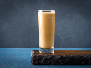 Long glass with coffee drink and cream on dark blue and black textured background