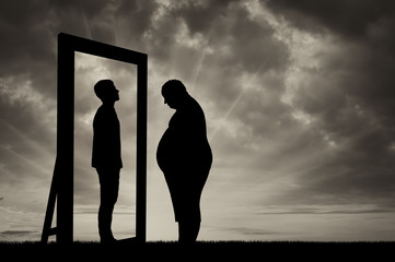 Fat sad man and his reflection in mirror of a normal man