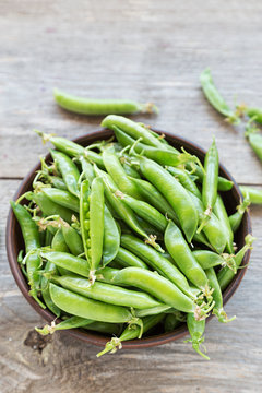 young peas in a clay plate on a wooden table