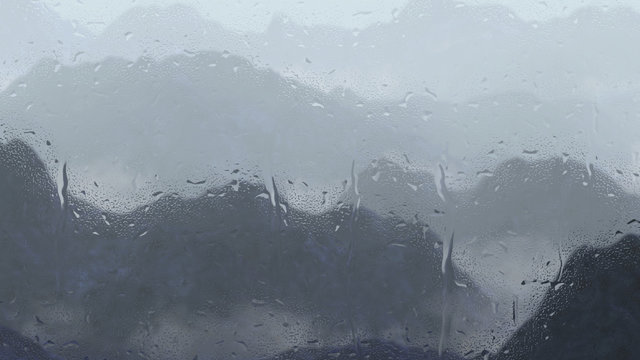 Fototapeta rain drops on a window with serene landscape and low crawling fog in the mountains
