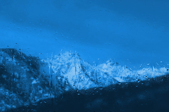 Fototapeta raindrops on a window with snowy blue mountain landscape outside