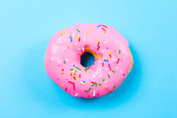 Pink round donut on blue background. Flat lay, top view.