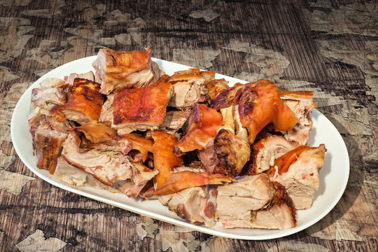 Plateful of Spit Roasted Pork Shoulder Slices Set on Old Cracked Flaky Wooden Garden Table