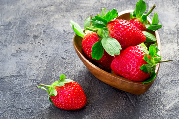 Ripe strawberries in a bowl in the shape of heart, copy space