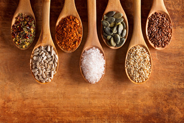 Food ingredients in wooden spoon on wooden background. Flax, pumpkin seed, sunflower seed, sesame and himalayan salt.