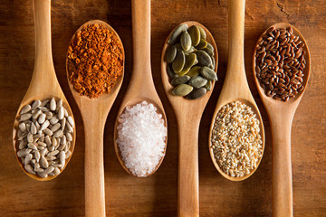 Food ingredients in wooden spoon on wooden background. Flax, pumpkin seed, sunflower seed, sesame and himalayan salt.
