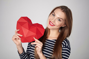 Smiling woman holding red polygonal paper heart shape