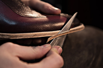 shoemaker makes shoes for men He cuts off excess and forms  shoe soles - Powered by Adobe