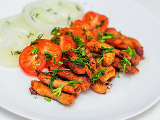 Fried pieces of pork schnitzel with cherry tomatoes and onion rings