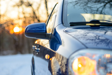 Close up Image of Side Rear-view Mirror on a Car in the Winter Landscape with Evening Sun