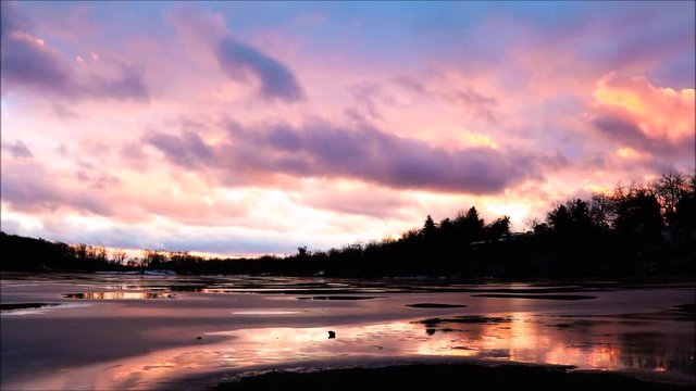 Magnificent sunset reflects over frozen lake
