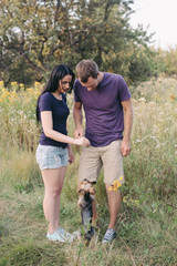 Naklejka na ściany i meble Young happy couple posing with their dog - yorkshire terrier on nature,love,lifestyle,relationship