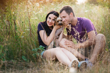Young happy couple posing with their dog - yorkshire terrier on nature,love,lifestyle,relationship