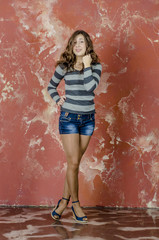 Young cheerful girl in denim shorts and a striped sweater walking in the youthful style
