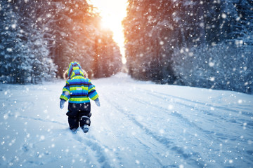 Boy in knitted hat, gloves and scarf outdoors at snowfall