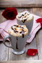 S'mores drink. Two mugs of hot chocolate with marshmallows on a wooden table. Cocoa. Rose petals. Valentine.