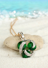 Jewellery pendant on sand beach with sea background, soft focus