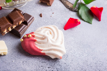 Homemade meringues in heart shape on light stone background. Valentines day concept, copy space.