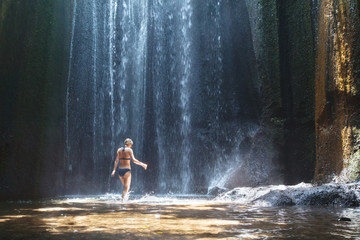 beautiful waterfall in Bali, woman in bikini bathing and swimming in the water