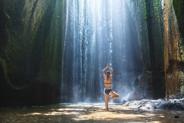 yoga, beautiful woman practices in waterfall, body and mind harmony in the nature