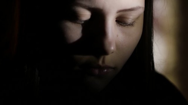 3Closeup portrait of a depressed teen girl in the dark. 4K UHD.