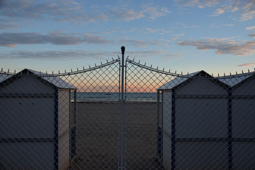 Fototapeta premium wooden beach huts on an empty beach at sunset