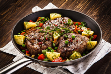 Grilled steak, baked potatoes and vegetables
