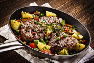 Grilled steak, baked potatoes and vegetables