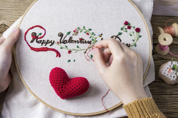 Young woman hands are embroidered happy valentines day