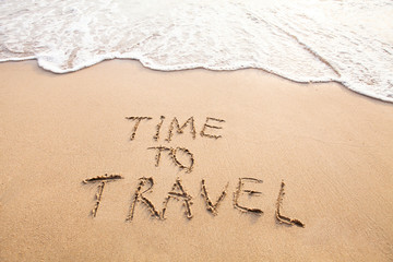 Fototapeta na wymiar time to travel, concept text drawn on sand of beach