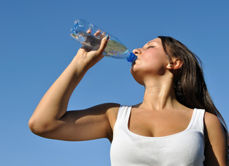 young athletic woman drinks cold water in hot day