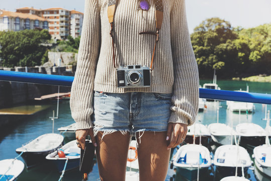 Tourist traveler photographer making pictures sea scape on vintage photo camera on background yacht and boat piar, hipster girl enjoying nature holiday, mockup ocean waves view, blurred backdrop