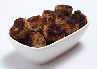 fried meatballs in white bowl on a white background