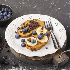 Healthy breakfast or snack. Two toast cereal bread with banana, blueberries and chocolate drops. Top view. Flat