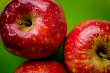 Three red apple on a green background. Close-up view from top.