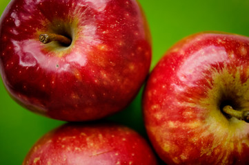 Three red apple on a green background. Close-up view from top.