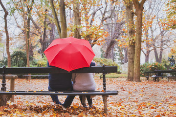 elderly retired couple sitting together on the bench in autumn park, love concept