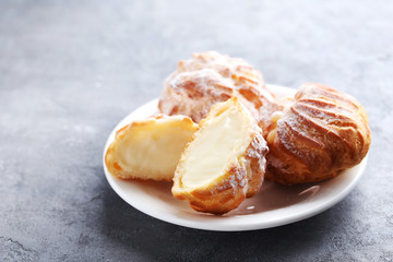 Homemade profiteroles with cream on grey wooden table