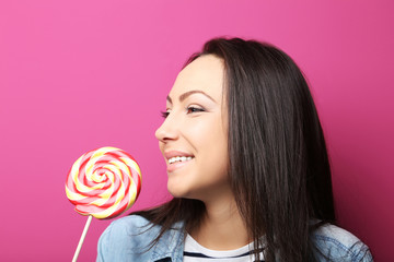 Young woman with lollipop on pink background