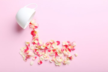 Rose petals and white cup on a pink background
