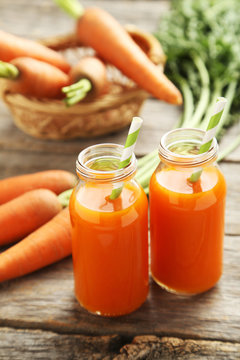 Fresh carrot juice in bottles on a grey wooden table