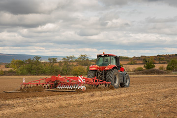 Obraz premium Farmer in tractor preparing land with seedbed cultivator