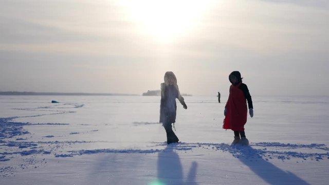 Two beautiful girls on the lake dabble in in the snow, jump, somersault, 4k