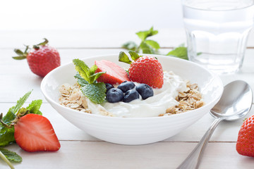 Morning healthy breakfast with muesli and berries on the white background. Side view